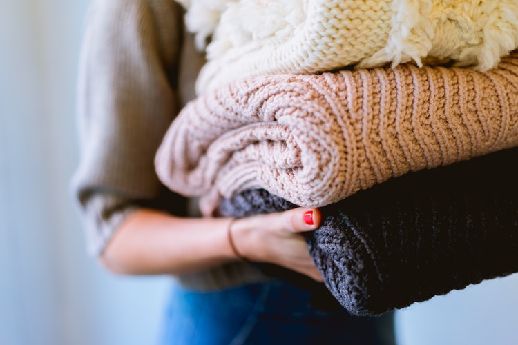 Idées de photos d'automne pour instagram - une fille avec des pulls pliés dans ses mains